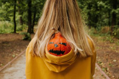 Halloween pumpkin. Woman holding a scary face pumpkin. Happy Halloween party holiday. Celebrate annual in October 31. Autumn season. Fall color, orange and yellow. Trick or treat. Young girl outdoors