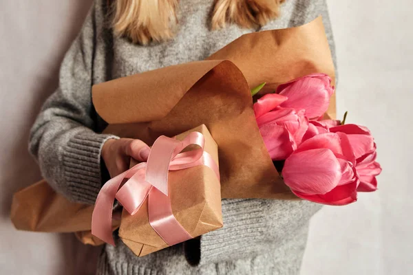 Happy woman holds tulips in her hands. Florist girl gathered a bouquet. Beautiful pink flowers. Blossom petal. Gift for the holiday celebration, springtime mood. Romantic surprise from a loved one