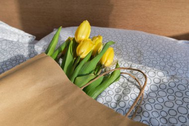 Kese kağıdında sarı laleler. Güneşin altında güzel bahar taze çiçekleri. Çiçeksel romantik ruh hali. Kadınlar için güzel bir hediye. Bahar çiçekleri, laleler. Kadınların bayram kutlamaları