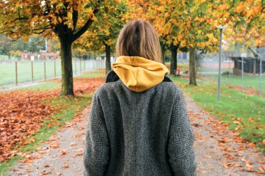 Güzel beyaz bir kadın halka açık bir parkta yürüyor. Açık hava aktiviteleri, rahat yaşam tarzı. Şehirde iyi tatiller. Sonbahar yürüyüşü. Şirin kız havadan ve temiz havadan hoşlanıyor. Yeşil doğada hafta sonu