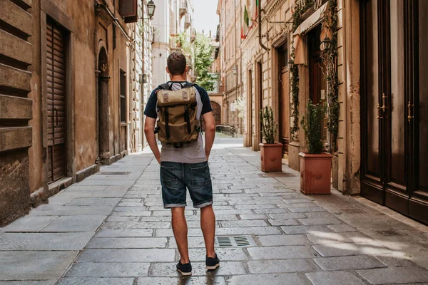 Sırt çantalı bir adam şehrin sokaklarında yürüyor. Turistler Avrupa 'da tatilin tadını çıkarırlar. Güzel eski tarihi mimari. İtalyan hafta sonu. Torino, İtalya 'ya git. Macera yaşam tarzı