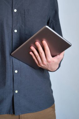 Elinde şık bir tablet tutan bir adam. Moda bir aleti olan bir iş adamı. Modern teknoloji, kablosuz internet. İş ve eğlence için mobil cihaz. Özgürlük yaşam tarzı, serbest çalışma