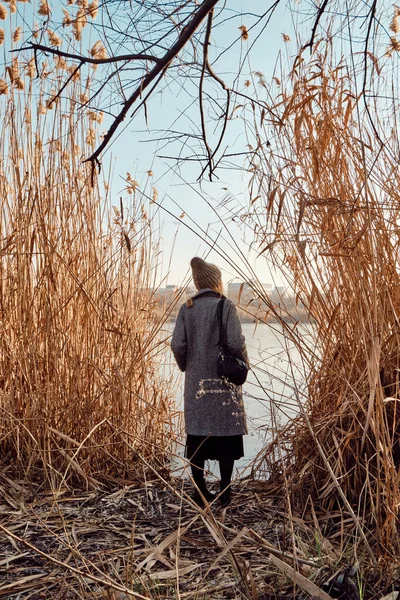 A woman walking in a field outdoors. Beautiful autumn landscape, fall foliage. Rural scenic sunset. Rest and recovery in the weekend. Stylish happiness  girl in comfortable clothes. Evening adventure