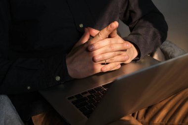 Dizüstü bilgisayarlı bir iş adamı. Freelancer evden iş yapıyor, uzaktan kumandayla. Erkekler ellerini bilgisayarın klavyesine koyup yakın plan çekiyorlar. Modern teknoloji, kablosuz iletişim. Sabah güneşi odada.