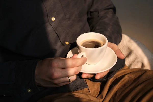 Bir fincan kahveyle şık bir adam. İş adamı kahvaltıdan sonra sabah kahvesini içiyor. Beyaz bardakta nefis sıcak espresso. Anın tadını çıkar, mola ver. Bağımsız yaşam tarzı. Sabah güneşi odada.