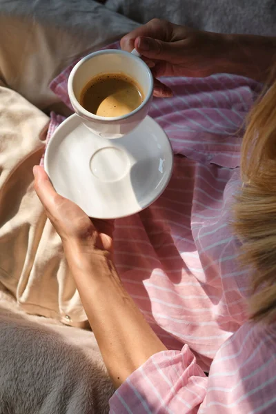 Beautiful woman with a cup of coffee. Businesswoman drink morning coffee after breakfast. Delicious hot espresso in white cup. Enjoy moment, take break. Freelancer lifestyle. Morning sun in the room