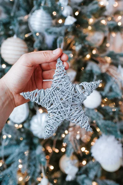 A man holds a beautiful Christmas star in his hands. Traditional Christmas tree decoration. Preparing for the celebration. Happy family holiday. Winter season lights. Stylish handmade star close-up