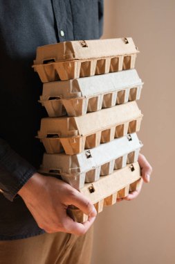 Tavuk yumurtalı karton kutular. Bir adam pişmemiş yumurtalarla dolu kutuları tutar. Doğal organik tarım ürünü. Paskalya tatiline hazırlanıyorum. Taze yemek teslimatı, karton paket. Yemek pişirmek için ham malzeme.