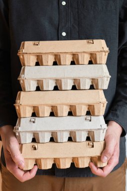 Tavuk yumurtalı karton kutular. Bir adam pişmemiş yumurtalarla dolu kutuları tutar. Doğal organik tarım ürünü. Paskalya tatiline hazırlanıyorum. Taze yemek teslimatı, karton paket. Yemek pişirmek için ham malzeme.