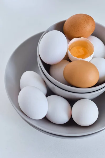 Chicken eggs on minimalist plates. Art photo with uncooked eggs on white table. Natural organic farm product. Preparing for Easter holiday. Kitchen art, dish on cuisine. Raw ingredient for cooking eat