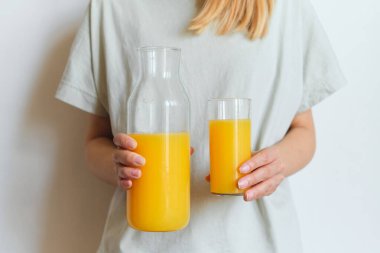 Kız elinde bir bardak portakal suyu tutuyor. Taze doğal portakal suyu. Kahvaltıda vitamin içeceği. Sağlıklı yaşam tarzı, organik diyet. Sabah sporundan sonra ferahlatıcı. Afiyet olsun.
