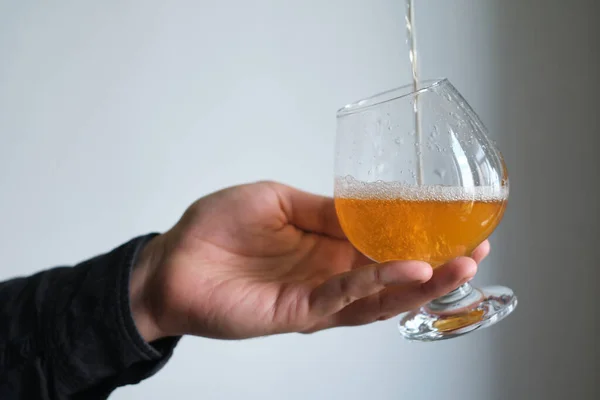 A glass of beer in the hands of a man. Tasting brewed craft beer. Lager beer with beautiful foam. Cold refreshment beverage. Alcohol drink from pub. Relaxation and enjoyment on beer degustation