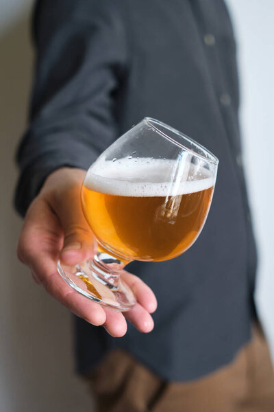Стакан пива в руках у мужчины. Дегустирую пиво. Лагерное пиво с красивой пеной. Холодный прохладительный напиток. Алкогольный напиток из паба. Отдых и наслаждение от дегустации пива
 