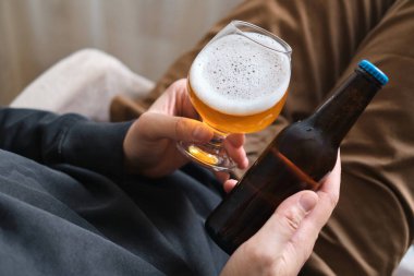 Bir adamın elinde bir bardak bira ve şişe. Bira tatmak için. Güzel köpüklü bira. Soğuk içecek içeceği. Alkol içeceği. Bira degulasyonunda rahatlama ve keyif