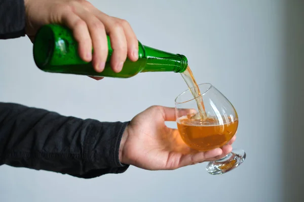 A glass of beer and bottle in the hands of a man. Tasting brewed craft beer. Lager beer with beautiful foam. Cold refreshment beverage. Alcohol drink. Relaxation and enjoyment on beer degustation