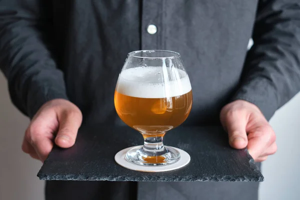 A glass of beer in the hands of a man. Tasting brewed craft beer. Lager beer with beautiful foam. Cold refreshment beverage. Alcohol drink from pub. Relaxation and enjoyment on beer degustation