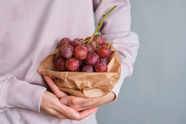 Bunch of grapes in the hands of a girl. Handpicked ripe grapes closeup. Red wine grapes. Fresh juicy berries. Healthy organic sweet fruit. Delicious autumn natural dessert. Vitamins diet for woman