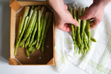 Bir adamın ellerinde yeşil kuşkonmaz. Bir sürü taze kuşkonmaz. Sağlıklı organik yiyecekler. Evde yemek pişirmek. Doğal vitaminler, yemek için ham malzeme. Özenle seçilmiş biyolojik kuşkonmaz.
