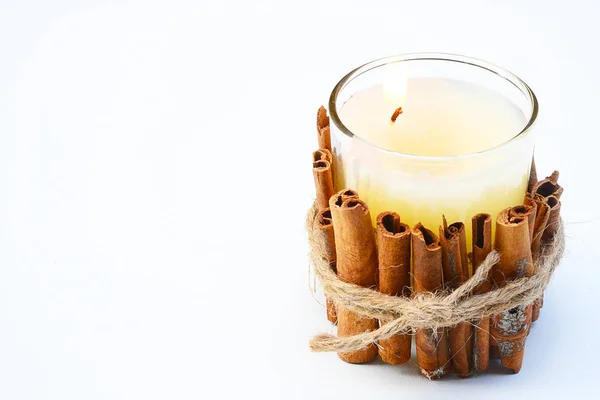 Candles decorated with cinnamon sticks on a white background.