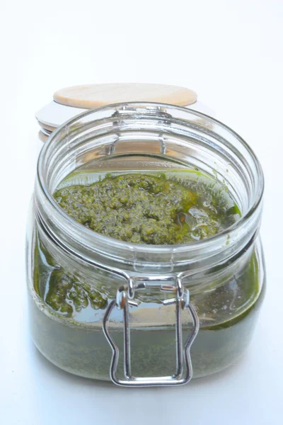 Salsa di pesto in un barattolo con parmigiano di pino e aglio sul tavolo di legno bianco — Foto Stock