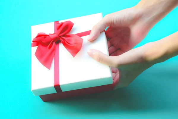 假日和惊奇的概念。女手拿盒子包装在白色和粉红色的纸，红色蝴蝶结 — 图库照片
