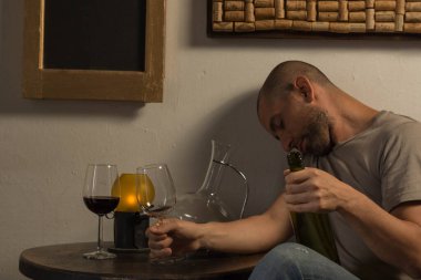 Masada elinde bardak ve şişe tutan sarhoş bir adam.