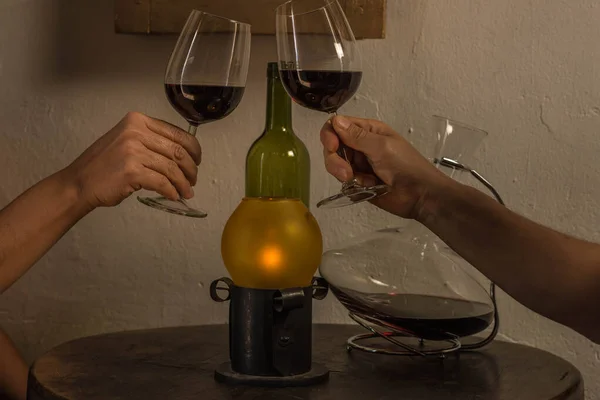 Ręce mężczyzny i kobiety trzymających kieliszki wina na stole z pustą butelką, pojemnikiem na wino i starą lampą — Zdjęcie stockowe