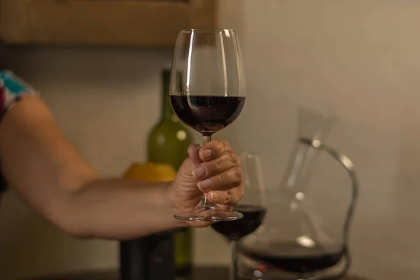Eine Frau hält ein Weinglas über einen Holztisch mit Flasche, Weinbehälter und einer alten Lampe — Stockfoto