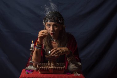 Gypsy fortune teller or esoteric oracle holding a smoking piece of wood and a magic crystal ball clipart