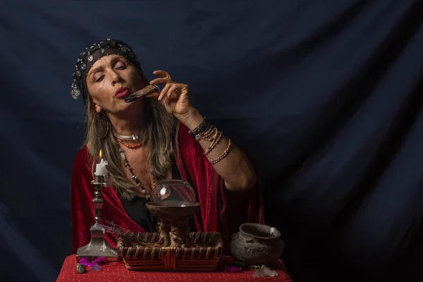 Çingene falcı ya da esrarengiz kahin elinde odun tutuyor ve üflüyor.