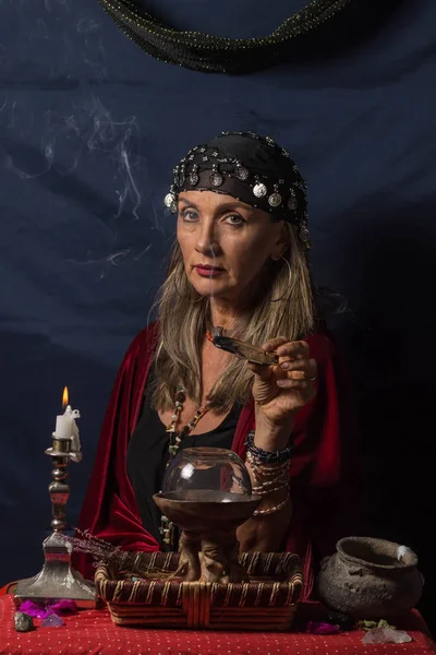 Çingene falcı ya da esrarengiz kahin elinde dumanı tüten odun tutuyor