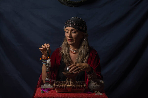 Цыганская гадалка или эзотерический оракул, держащий дымящийся кусок дерева и волшебный хрустальный шар
