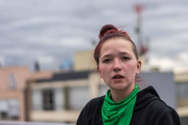 Boynunda yeşil bandana olan genç bir kadın eylemci. Feminizm kavramı