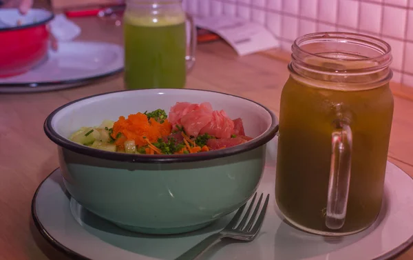 Healthy raw food clean eating selection: salmon, vegetable and fruits in a bowl with a green beverage in a glass jar. Balanced meal