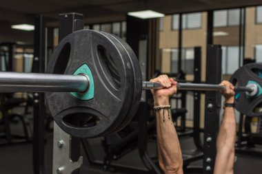 Ağırlık diski olan halter ve spor salonunun içinde tutan kaslı eller. Seçici odak