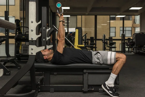 Spor salonunda halter kaldıran genç bir Latin. Spor salonu göğüs egzersizleri.