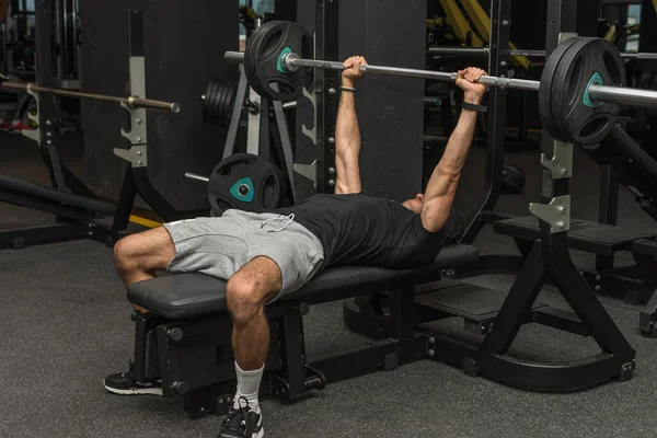 Spor salonunda halter kaldıran genç bir Latin. Spor salonu göğüs egzersizleri. Seçici odak
