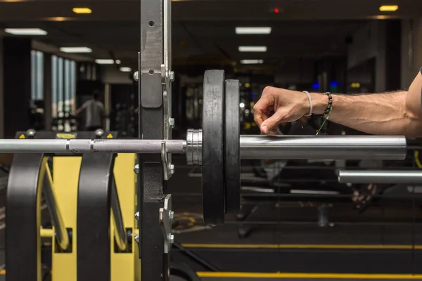 Halterin üzerine ağır bir disk takan bir adamın kırpılmış görüntüsü