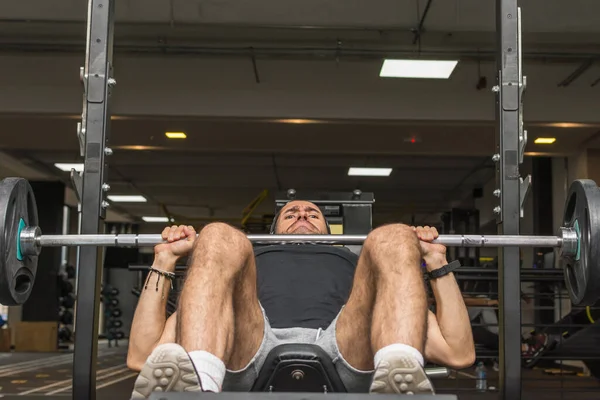 Spor salonunda halter kaldıran genç bir Latin. Spor salonu göğüs egzersizleri. Seçici odak