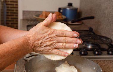 Tipik ev yapımı Kolombiya arepası yapmak için mısır hamurlu kadın elleri