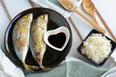 Pirinç ve aşk seramik Kupası'nda siyah soslu kızarmış uskumru götürüyor üstten görünüm avlanır. Mutlu ahşap çatal ve kaşık, yeşil masa örtüsü ile dekore edilmiştir. Aşk ve ilişki hakkında kavramı. 