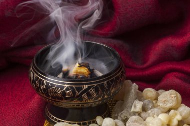 Sıcak kömürde tütsü yanıyor. Tütsü, dini ayinler, tütsü ve parfümler için kullanılan aromatik bir reçinedir..