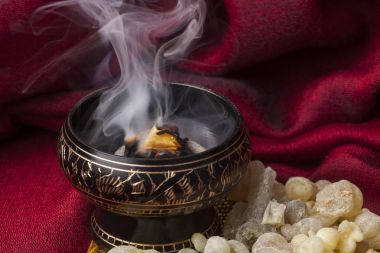 Frankincense burning on a hot coal. Frankincense is an aromatic resin, used for religious rites, incense and perfumes. clipart