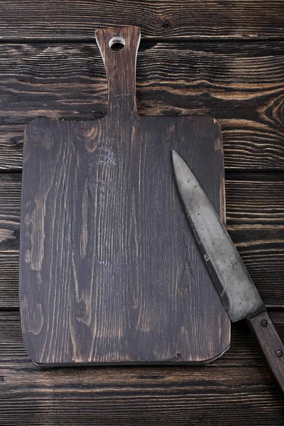 Cutting board with a knife for slicing on the old wooden background with space for text — Stock Photo, Image