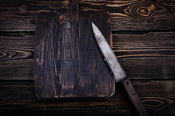 Cutting board with a knife on old wooden background — Stock Photo, Image
