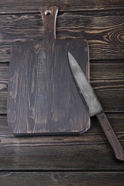 Cutting board with a knife for slicing on the old wooden background with space for text — Stock Photo, Image