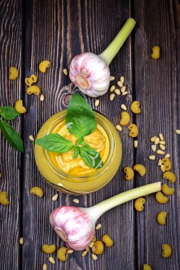 Pesto soslu makarna üzerine koyu ahşap arka plan için. Sedir fındık, fesleğen, sarımsak, zeytinyağı, peynir