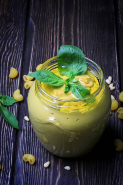 Pesto soslu makarna üzerine koyu ahşap arka plan için. Sedir fındık, fesleğen, sarımsak, zeytinyağı, peynir