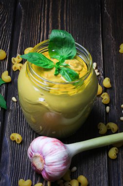 Pesto soslu makarna üzerine koyu ahşap arka plan için. Sedir fındık, fesleğen, sarımsak, zeytinyağı, peynir