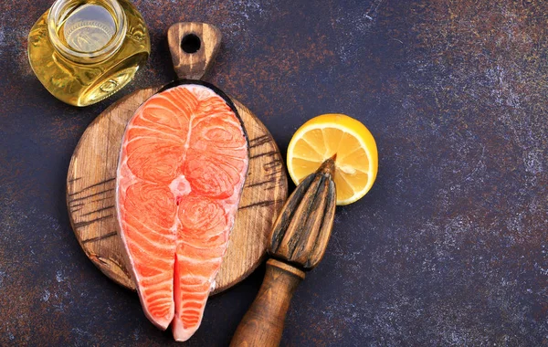Koyu arka plan üstten görünüm üzerinde limon ve zeytin yağı ile Çiğ somon biftek.